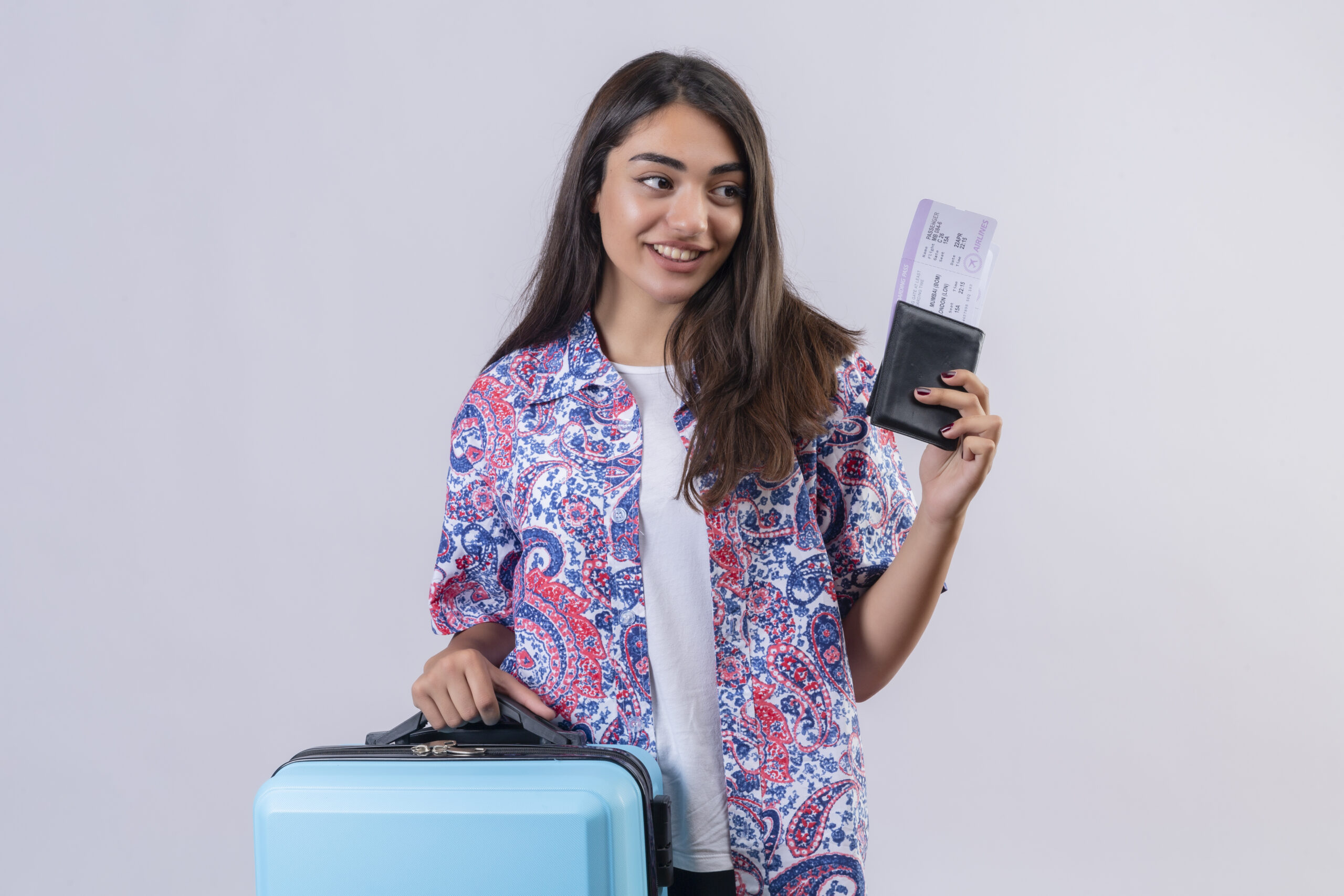beautiful tourist woman holding travel suitcase and passport with tickets looking aside with smile on face happy and positive travel concept standing over white background